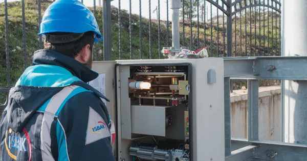 A professional electrician wearing a hard hat inspects an outdoor fuse box ensuring safety. an electrician inspecting a fuse box