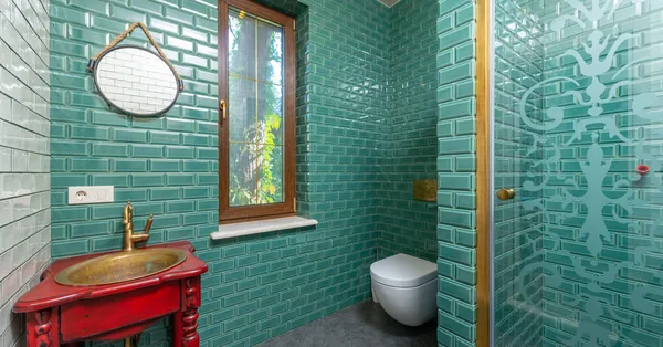 Modern bathroom with green tiled walls, gold fixtures, and elegant decor. green tiled wall in the bathroom