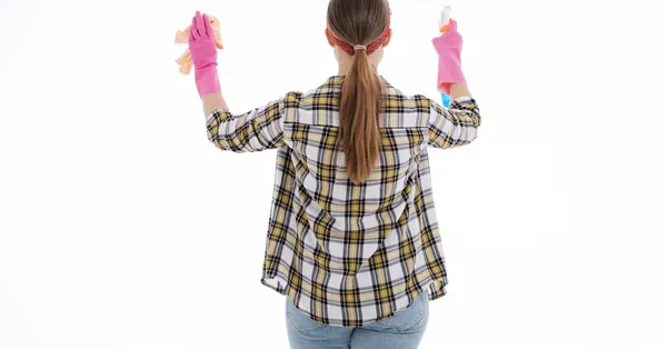 Back view of a woman in latex gloves cleaning with spray and cloth, indoor studio shot. a woman in plaid shirt