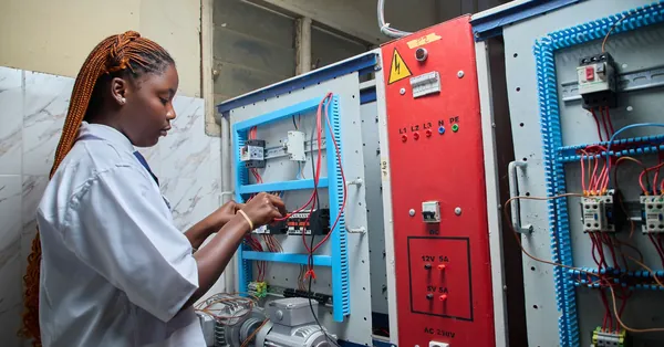 Young female technician repairing electrical control panel in industrial setting. female technician working on electrical control panel